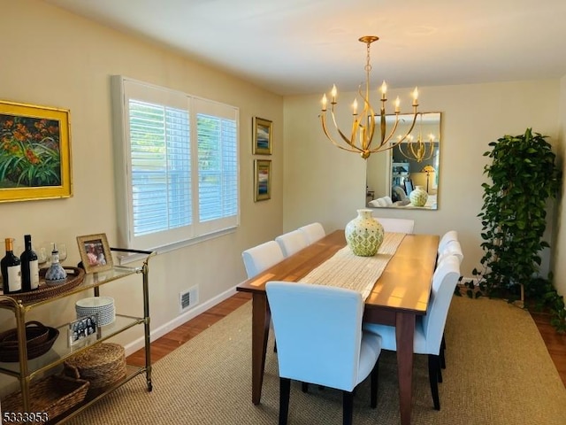 dining space with a chandelier, visible vents, baseboards, and wood finished floors