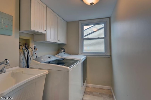 clothes washing area featuring washer and clothes dryer, cabinet space, baseboards, and a sink