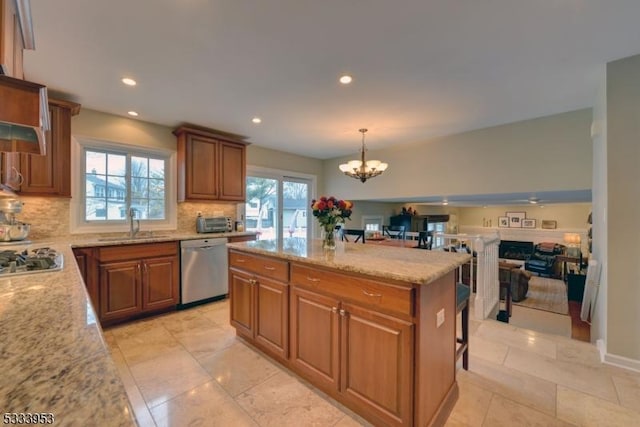 kitchen featuring light stone counters, stainless steel appliances, brown cabinetry, and a sink