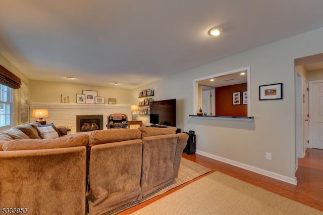 living room featuring a fireplace, baseboards, and wood finished floors