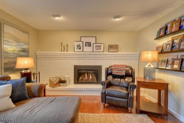 sitting room with a fireplace, baseboards, and wood finished floors