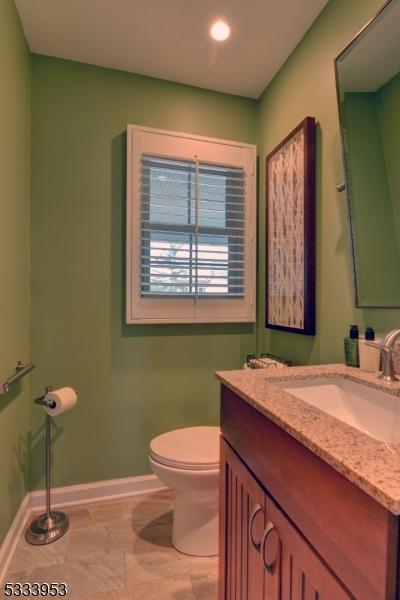 bathroom with baseboards, toilet, and vanity