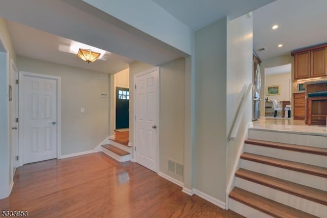 stairs featuring recessed lighting, wood finished floors, visible vents, and baseboards