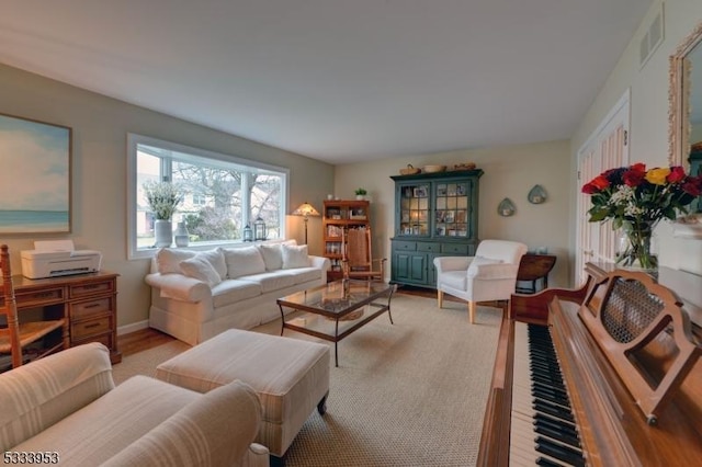 living room featuring visible vents, light wood-style flooring, and baseboards