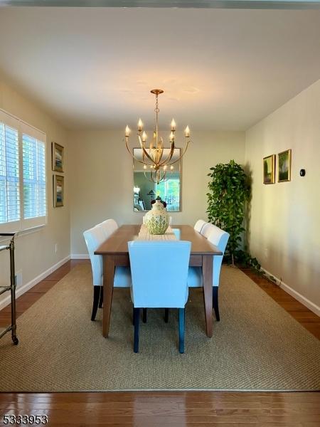 dining space with an inviting chandelier, wood finished floors, and baseboards