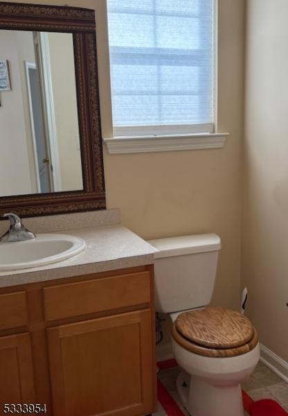 bathroom with toilet, tile patterned floors, baseboards, and vanity