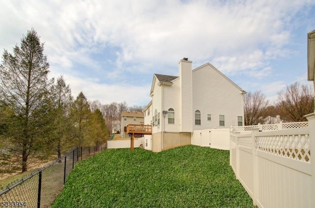 view of side of property with a lawn, a chimney, and fence