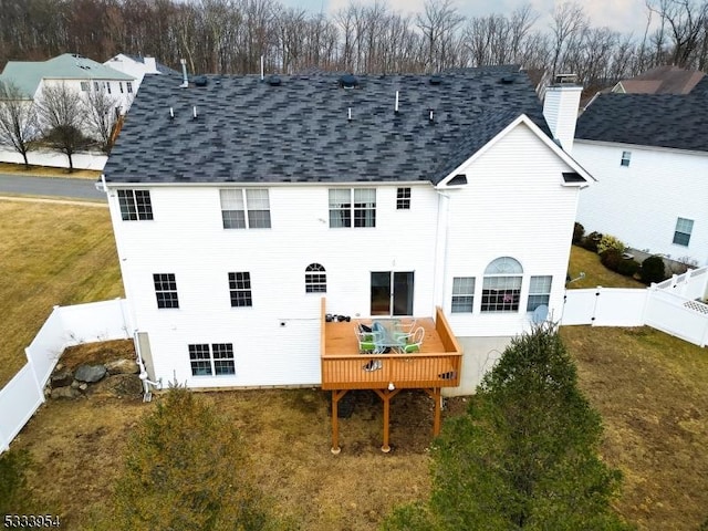 rear view of property with a shingled roof, a fenced backyard, a gate, a deck, and a yard