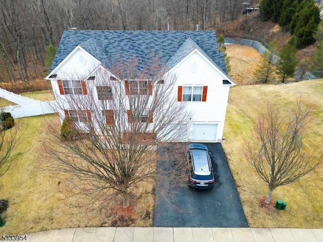 view of front of house with driveway, a shingled roof, fence, and an attached garage