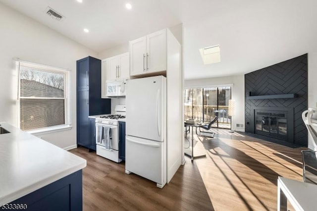 kitchen with white appliances, white cabinetry, a large fireplace, blue cabinets, and dark hardwood / wood-style flooring