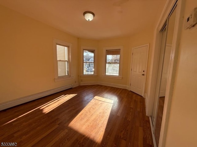 spare room with dark hardwood / wood-style flooring and baseboard heating