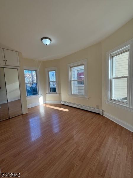 unfurnished bedroom with a baseboard radiator and light hardwood / wood-style floors