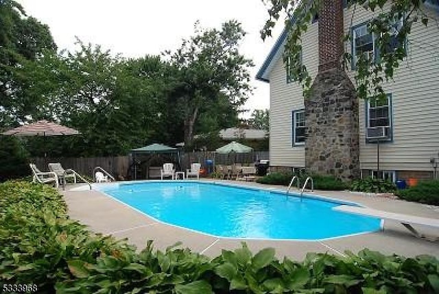 view of swimming pool featuring a patio area and a diving board