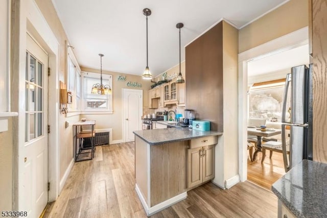 kitchen featuring radiator heating unit, pendant lighting, sink, dark stone countertops, and light hardwood / wood-style floors