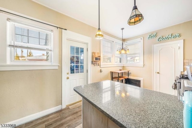 kitchen with pendant lighting, hardwood / wood-style floors, and dark stone counters