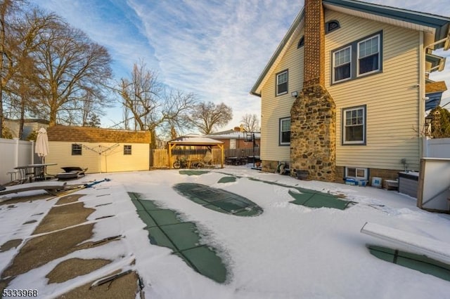 snow covered rear of property featuring a gazebo and a shed