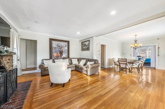 living room featuring an inviting chandelier, ornamental molding, a fireplace, and light hardwood / wood-style floors