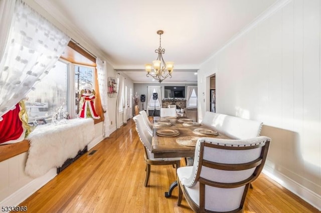 dining room featuring ornamental molding, a chandelier, and light wood-type flooring