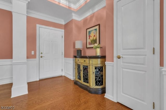 foyer with hardwood / wood-style floors, crown molding, and ornate columns