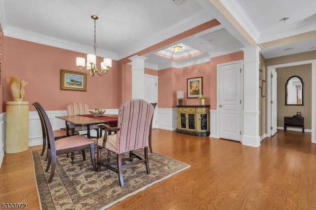 dining area with ornate columns, crown molding, hardwood / wood-style floors, and a notable chandelier