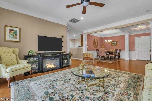 living room with ornate columns, crown molding, wood-type flooring, and ceiling fan with notable chandelier