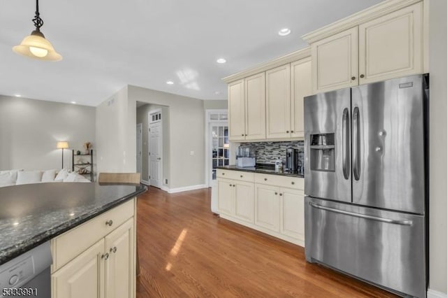 kitchen with decorative light fixtures, dark stone countertops, stainless steel fridge, dishwashing machine, and cream cabinets