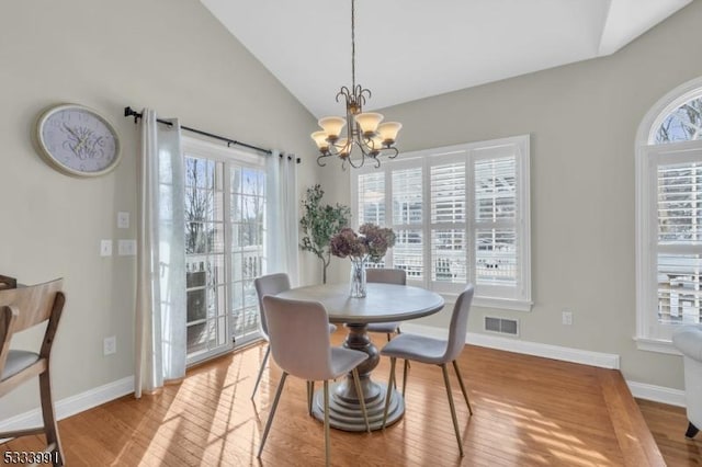 dining space featuring lofted ceiling, a notable chandelier, and light wood-type flooring