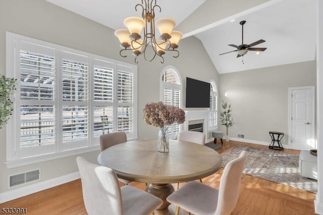 dining area featuring ceiling fan with notable chandelier, vaulted ceiling, and light hardwood / wood-style floors