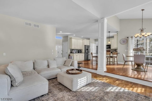 living room featuring vaulted ceiling, a notable chandelier, and light hardwood / wood-style floors