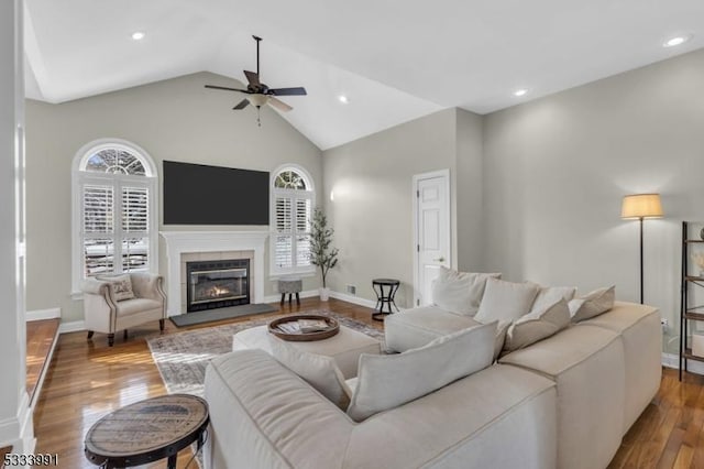 living room with hardwood / wood-style flooring, ceiling fan, vaulted ceiling, and a tile fireplace