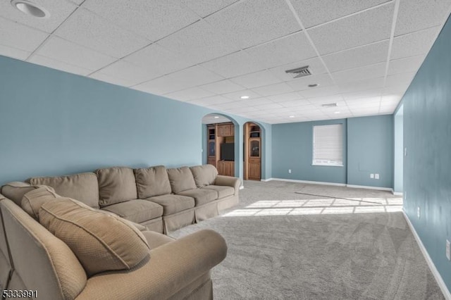 living room with a drop ceiling and light colored carpet