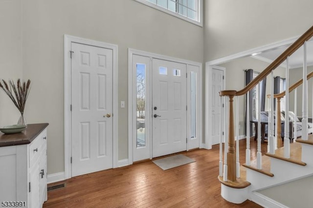 entrance foyer featuring a towering ceiling and wood-type flooring