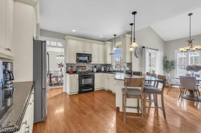 kitchen with decorative backsplash, a chandelier, hanging light fixtures, and black appliances