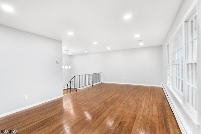 empty room featuring baseboard heating and wood-type flooring