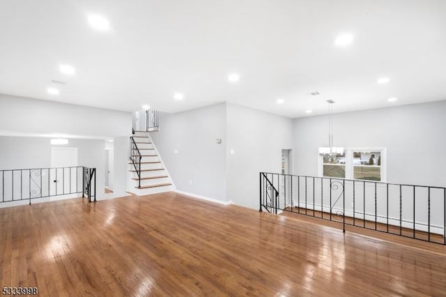 empty room with wood-type flooring and an inviting chandelier