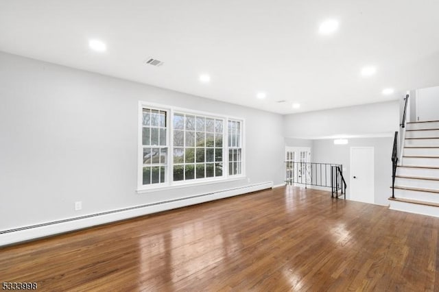 unfurnished living room featuring hardwood / wood-style floors and a baseboard heating unit