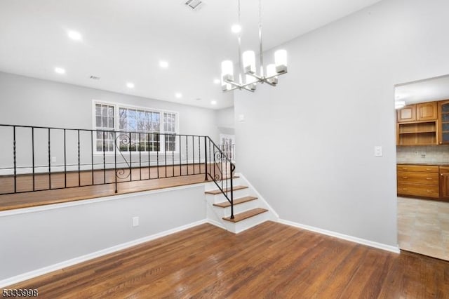 stairway featuring an inviting chandelier and wood-type flooring