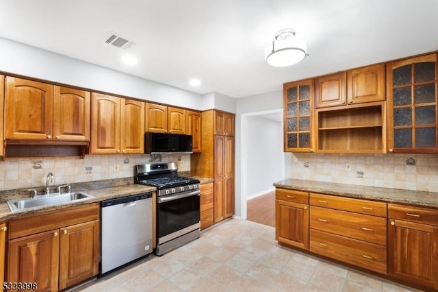 kitchen with stainless steel appliances, sink, light stone counters, and decorative backsplash