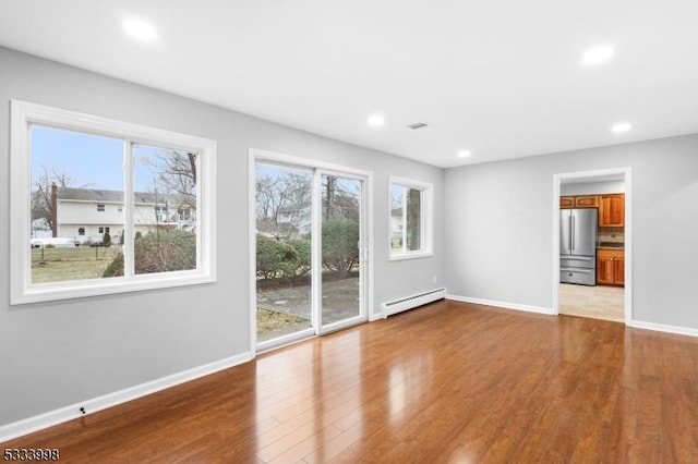 unfurnished living room featuring light hardwood / wood-style floors and a baseboard heating unit