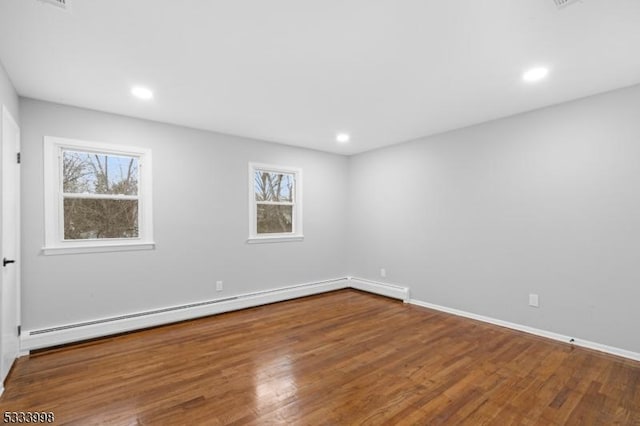 spare room featuring a baseboard heating unit and hardwood / wood-style flooring