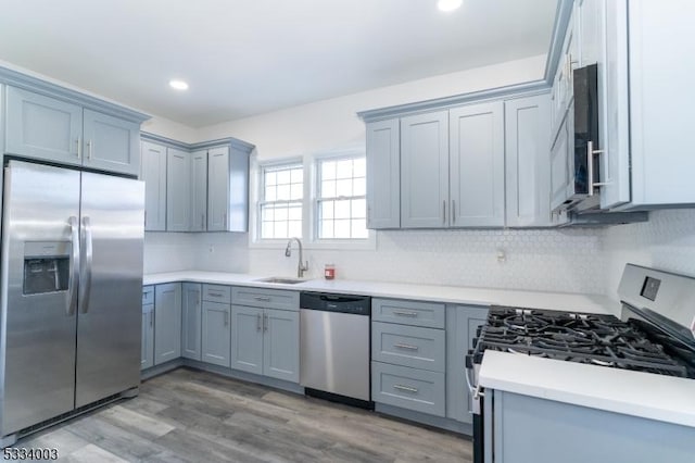 kitchen with sink, backsplash, wood-type flooring, and appliances with stainless steel finishes