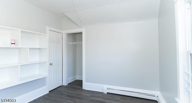 unfurnished bedroom featuring a closet, a baseboard heating unit, and dark wood-type flooring