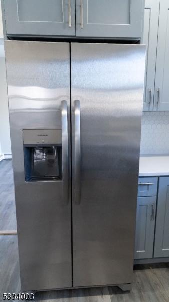 details with wood-type flooring, gray cabinetry, stainless steel fridge with ice dispenser, and tasteful backsplash