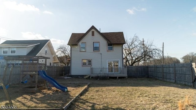 back of house featuring a playground and a lawn