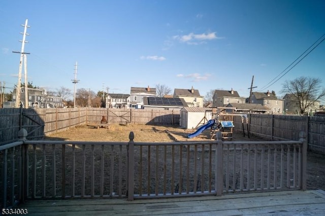 view of yard with a playground, a deck, and a storage unit