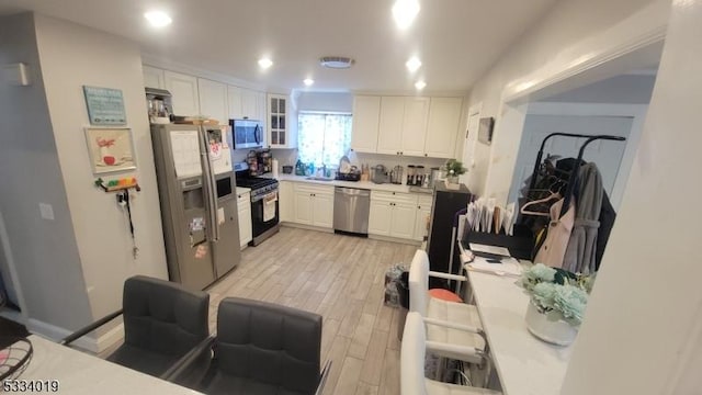 kitchen featuring white cabinets, stainless steel appliances, light hardwood / wood-style flooring, and sink