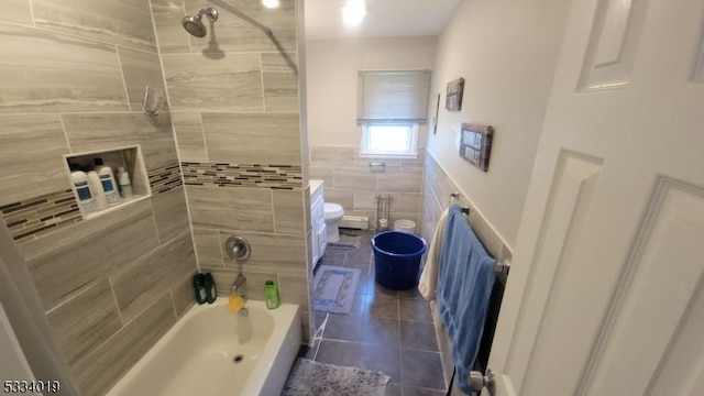 bathroom featuring tile patterned floors, toilet, tile walls, and tiled shower / bath combo