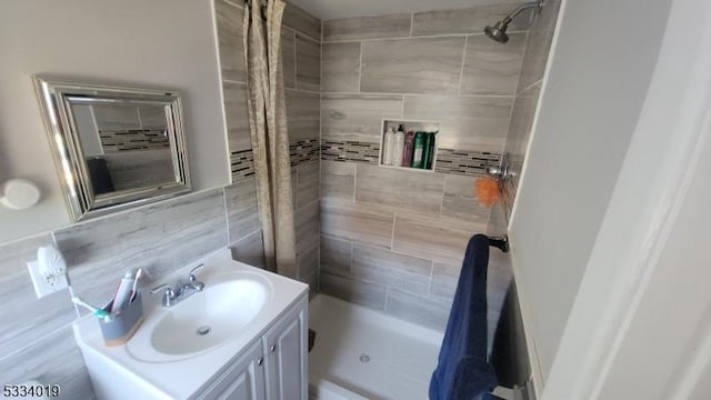 bathroom with curtained shower, decorative backsplash, tile walls, and vanity