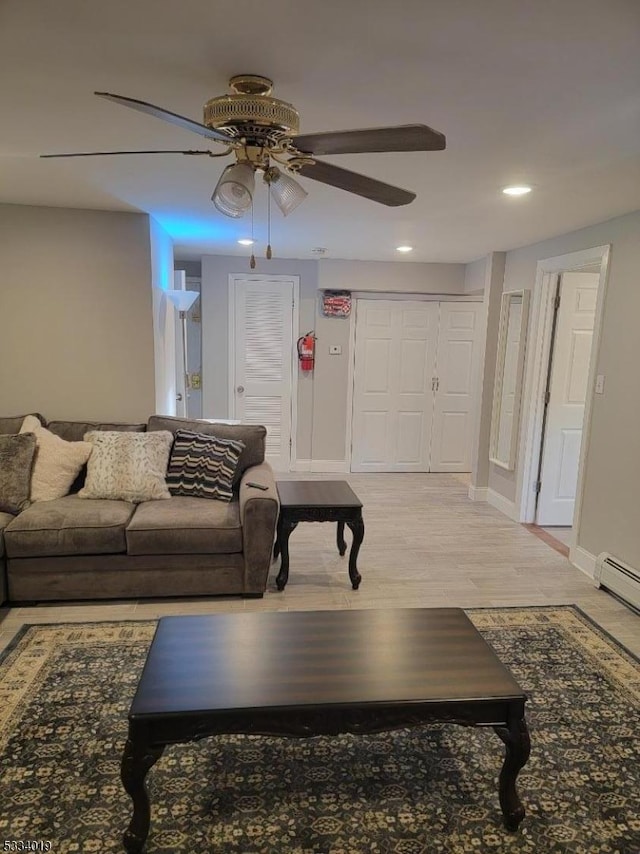 living room featuring ceiling fan, baseboard heating, and light wood-type flooring