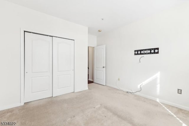 unfurnished bedroom featuring light carpet and a closet